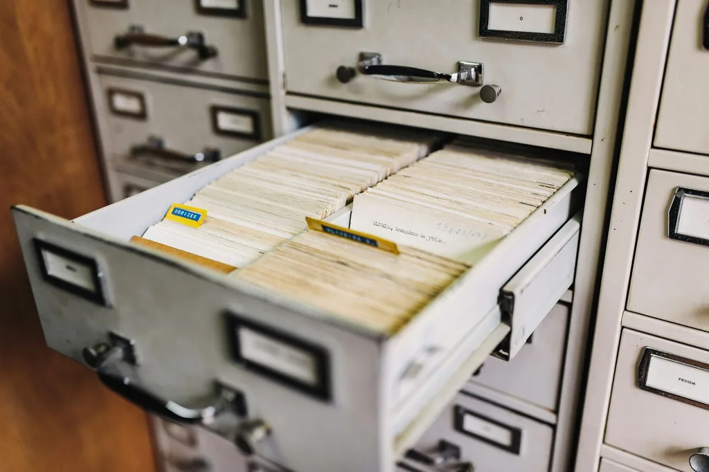 Open filing cabinet drawer packed with aged index cards and tabs.