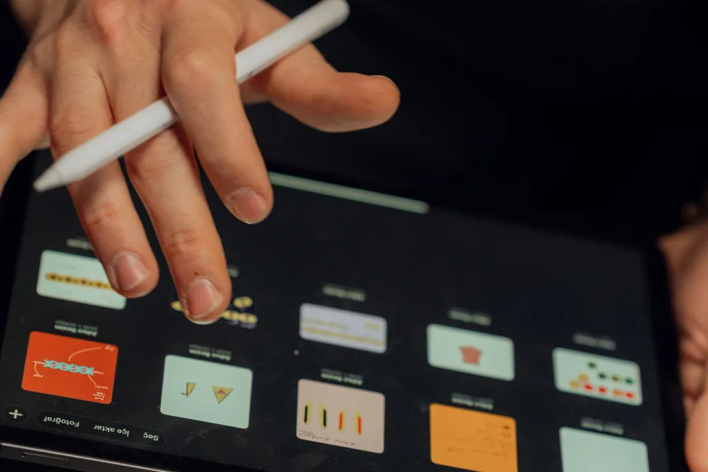 A hand with a stylus browses a grid of documents on a tablet in dark mode.