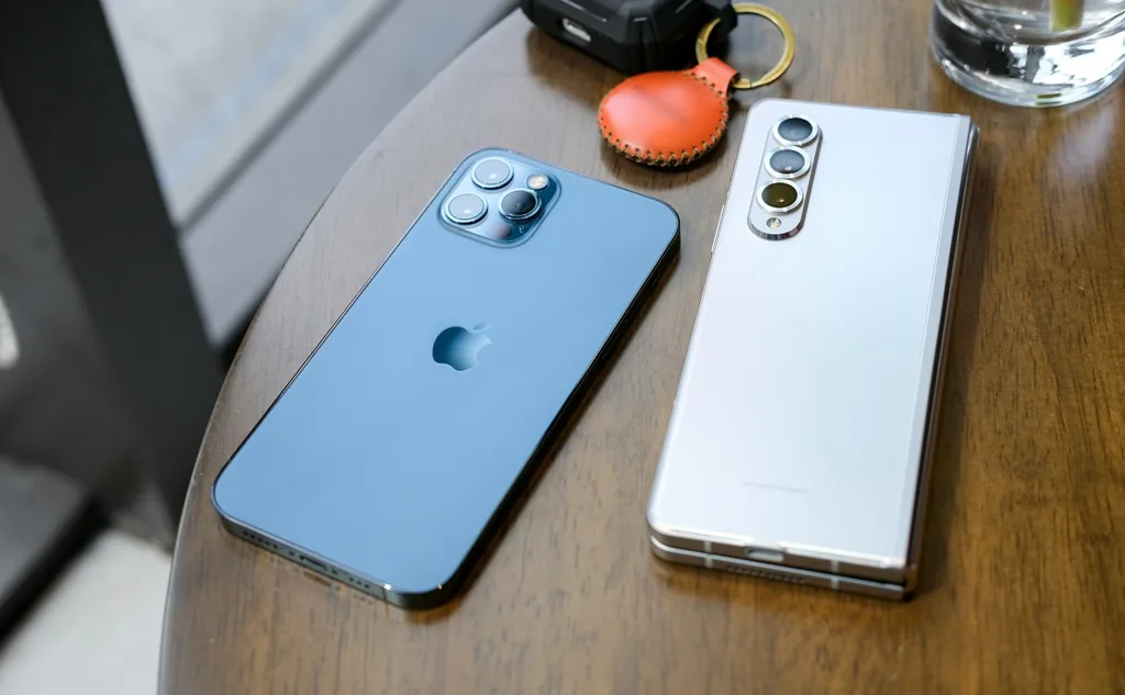 An iPhone and a Samsung Android phone lie side by side on a wooden café table.